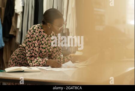 African female clothing designer looking at color samples in her studio Stock Photo