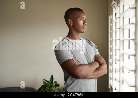 Young African man looking out through a window at home Stock Photo