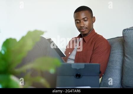 Young African man working from home using two tablets Stock Photo