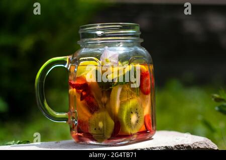 A Jar of glass, delicious detox drink with red, orange and yellow fruits, standing on the Stone. Selective Focus Glasses. Stock Photo