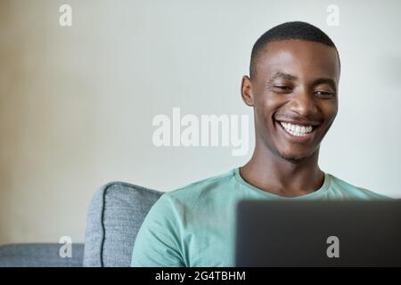 Smiling young African man working on a laptop at home Stock Photo