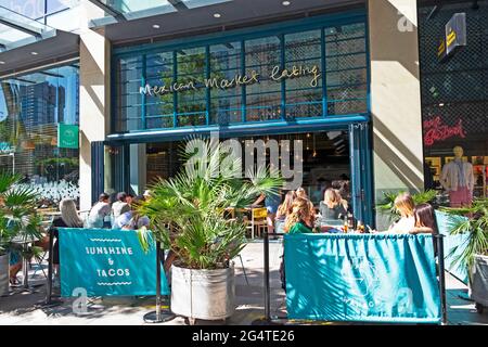Young men people social distancing outside walking past outdoor restaurant tables and chairs in Cardiff City Centre Wales UK    KATHY DEWITT