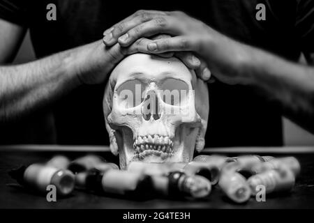Tattoo artist folded hands on plaster skull surrounded by typewriter ink, black and white photo. Stock Photo
