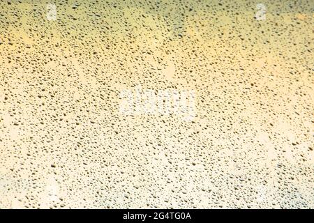 Rain drops on window glasses surface with warm shade background Stock Photo