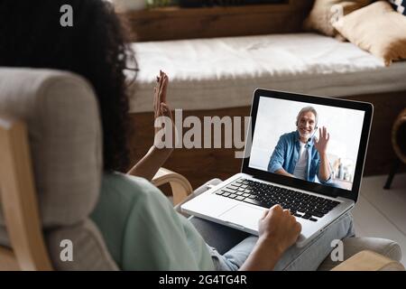 Laptop screen over woman shoulder view, communication group videocall conversation Stock Photo