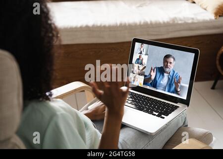 Laptop screen over woman shoulder view, communication group videocall conversation Stock Photo