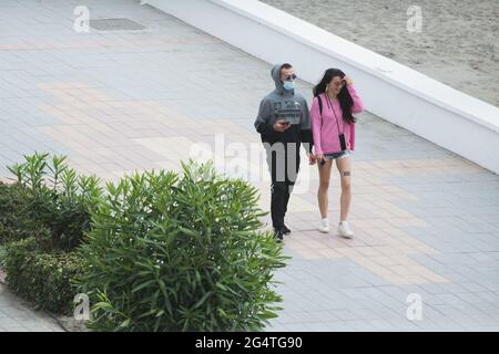 Torrox, Málaga, Spain; June 19 2021: A couple strolls along the promenade next to the beach Stock Photo