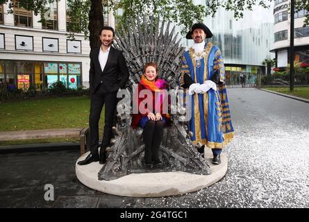 London, UK.  Alex Zane,  The Lord Mayor of Westminster Jonathan Glanz and Chief Executive á of Heart of London Business Alliance Ros Morgan with  The Game of Thrones chair as seen in the HBO television series goes on public display in LondonÕs Leicester Square. It commemorates 10 years since the TV show Game of Thrones  first aired and anticipates HBOÕs upcoming release of House of the Dragon in 2022. It will be displayed here until October 2021. 22nd June 2021. Ref:LMK11-SLIB220621-001.  Landmark Media. Editorial use only  WWW.LMKMEDIA.COM.