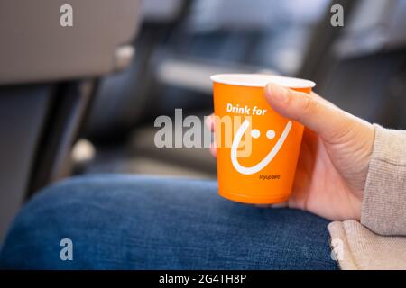 Kyiv, Ukraine - May 27, 2021: Woman's hand holds paper cup with Sky Up airline logo during flight. Stock Photo