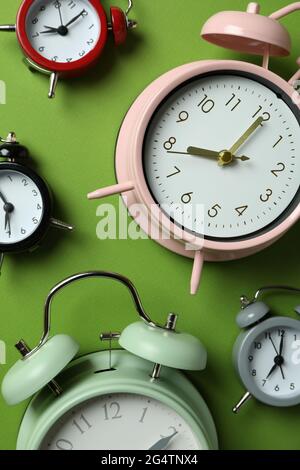 Different multicolor alarm clocks on green background Stock Photo