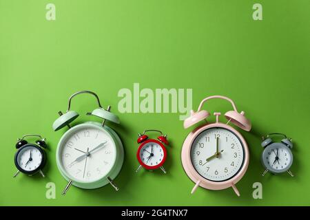 Different multicolor alarm clocks on green background Stock Photo