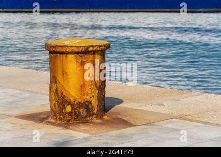 Very old rusty iron bollard on concrete marine dock for boat Stock Photo