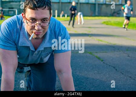 the face of a grinning man with a cigarette in his mouth at the stadium Stock Photo