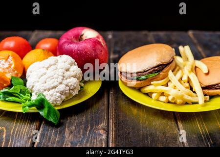 junk food or healthy vegetables and fruits on dark wooden table isolated Stock Photo