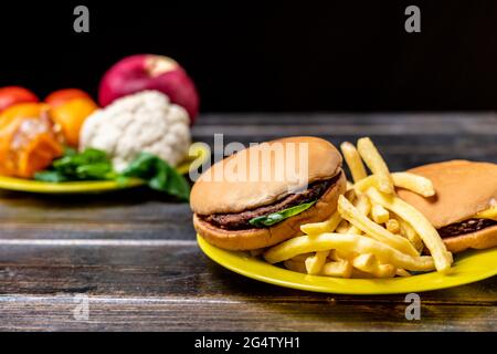 junk food or healthy vegetables and fruits on dark wooden table isolated Stock Photo
