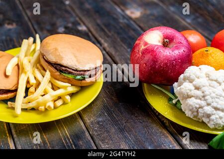 junk food or healthy vegetables and fruits on dark wooden table isolated Stock Photo