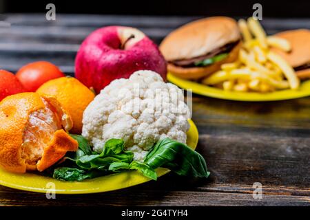 junk food or healthy vegetables and fruits on dark wooden table isolated Stock Photo