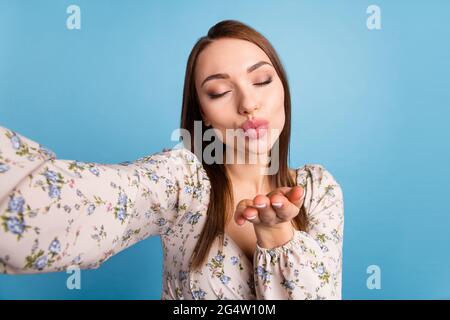 Photo of flirty brown hairdo millennial lady do selfie blow kiss wear floral blouse isolated on blue color background Stock Photo