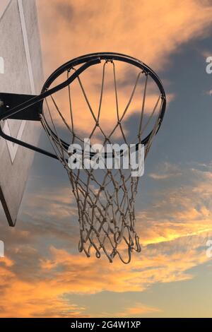 detail of a basketball hoop in the street at sunset on a sunny day with clouds with selective focus Stock Photo