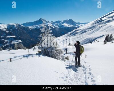 A lady snowshoe walker pauses to look at the view at Safienvalley in the Canton of Graubunden in the Swiss Alps, Switzerland