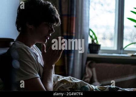 young man is praying in bed at home Stock Photo