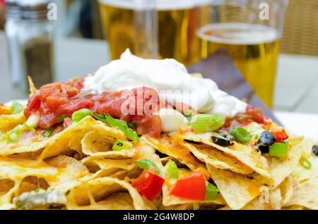 Appetizer or snack for drinking beer on patio made of nachos, sour cream, and jalapenos Stock Photo