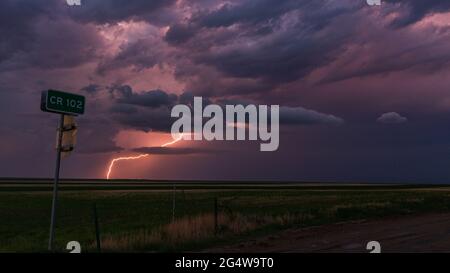 Lightning bolt strikes off in the distance lighting up a dark and ominous sky as a thunderstorm passes through eastern Colorado Stock Photo