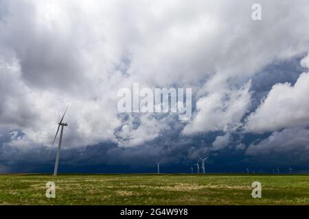 Ominous storms in the skies over the eastern Colorado plains with numerous windmills spread across the prairie Stock Photo