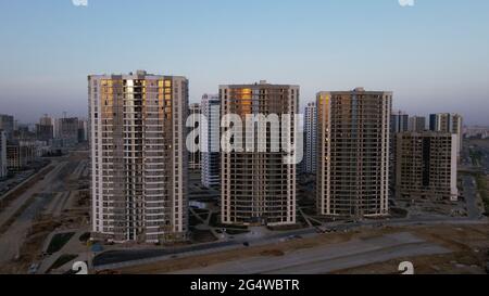 Construction of a new city block. New construction of modern multi-storey buildings. The setting sun is reflected in the windows of the houses. Aerial Stock Photo