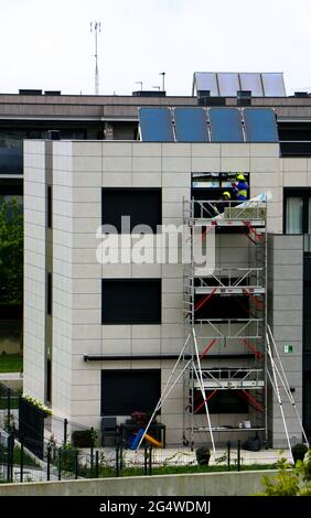 Two workmen repairing water ingression behind cladding on a 1 year old block of flats Santander Cantabria Spain Stock Photo