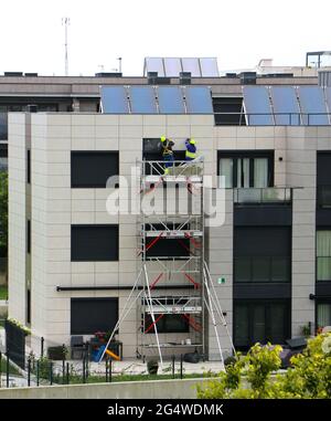 Two workmen repairing water ingression behind cladding on a 1 year old block of flats Santander Cantabria Spain Stock Photo