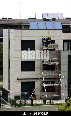 Two workmen repairing water ingression behind cladding on a 1 year old block of flats Santander Cantabria Spain Stock Photo