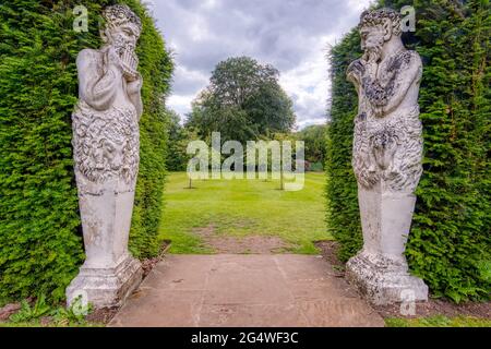 Pan piper statues adorn a garden entrance at Anglesey Abbey, a Jacobean-style country house at Lode, near Camdridge, UK, Stock Photo