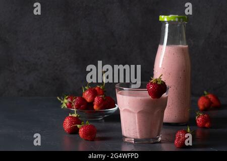 Indian strawberry lassi or smoothie on gray background. Traditional ayurvedic healthy drink with strawberries of yogurt and ice cube in bottle and Stock Photo