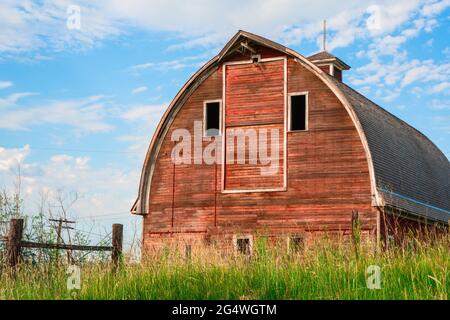 Abandoned old wooden red barn in rural farm landscape Stock Photo