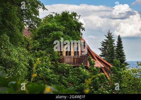 Wooden building hidden among the trees, Beskidy Mountains in the background Stock Photo
