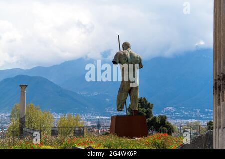 The bronze sculpture of Daedalus sculptor Igor Mitoraj donated to Pompeii. Pompeii ruins in Italy, a background of red poppies, mountains, cloudy sky Stock Photo