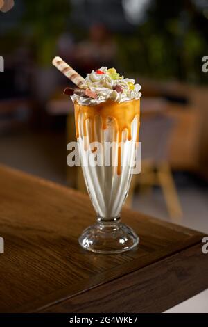 Extreme milkshake with marmalade and candy inside the interior of modern cafe. Stock Photo