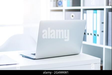 Modern laptop on white table in light office Stock Photo