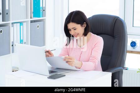 Beautiful woman working with papers in light room Stock Photo