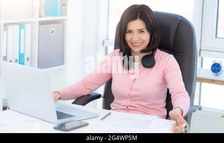 Cheerful business woman sitting in armchair at workplace Stock Photo