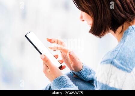 Woman using smartphone in light room Stock Photo