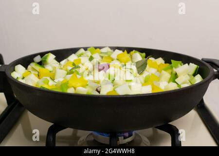 Diced zucchini and yellow and green peppers are simmered in a cast iron skillet. Spanish cuisine concept. Pisto manchego. Stock Photo
