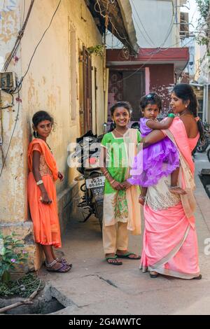 Indian mother and three daughters dressed in colourful saris and salwar kameez stand on street posing for photo, Trichy, Tamil Nadu, India Stock Photo