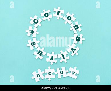 Circle made of white jigsaw puzzle pieces with word coronavirus on blue, top view Stock Photo