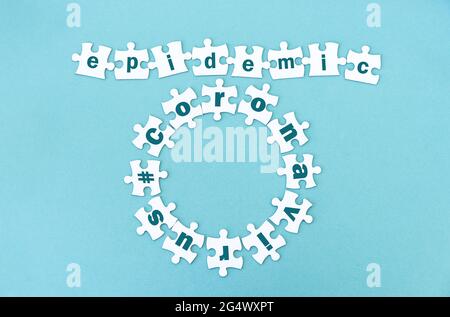 Circle and row made of white jigsaw puzzle pieces with word epidemic andcoronavirus on blue Stock Photo