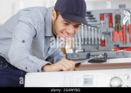 plumber installing washing machine in domestic bathroom Stock Photo