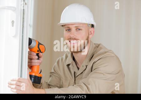 tradesman using cordless screwdriver to work on pvc door Stock Photo