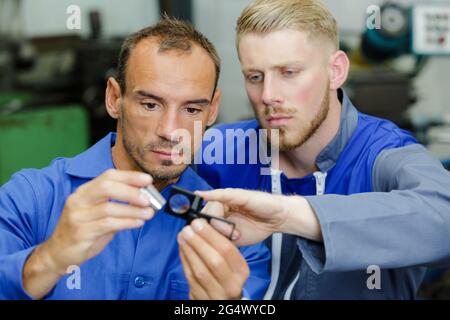 two mechanics examining part they are holding Stock Photo