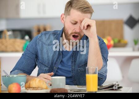 man falling asleep during his breakfast after overtime work Stock Photo